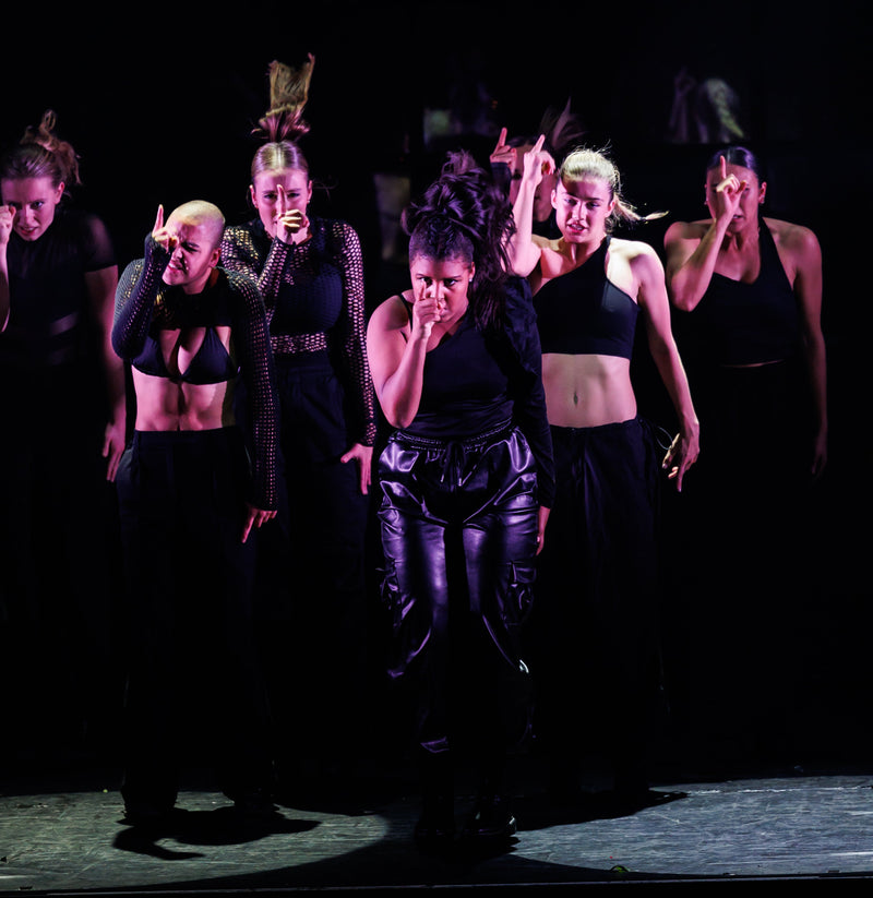 Group of performers on stage with dark lighting